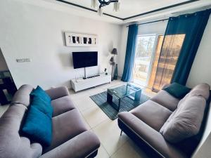 ein Wohnzimmer mit zwei Sofas und einem Fernseher in der Unterkunft Appartement vue sur la mer Almadies Dakar "Résidence les embruns" in Dakar