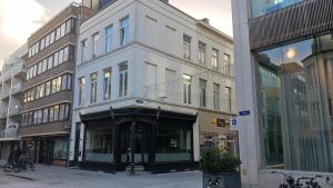 a white building on a city street with buildings at La Nonne Blanche in Ostend
