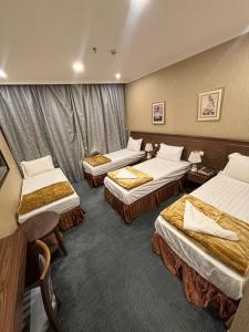 ein Hotelzimmer mit drei Betten in der Unterkunft فندق قلعة تاون هاوس توصيل مجاني للحرم 1 - Town House Palace Free Shuttle Service to Haram in Al ‘Azīzīyah
