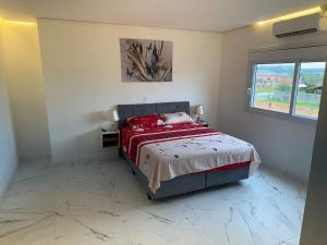 a bedroom with a bed with red sheets and a window at Casa completa para relaxar com a família in Passo De Torres