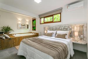 ein Schlafzimmer mit großem Bett und Badewanne in der Unterkunft Recanto das Palmeiras in Guarda do Embaú