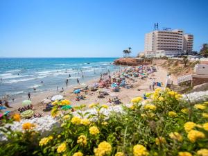 uma praia com uma grande multidão de pessoas e o oceano em Hotel Servigroup La Zenia em Playas de Orihuela