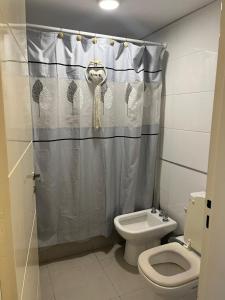 Un baño con inodoro y cortina de ducha. en Departamento Andy, en Villa Carlos Paz