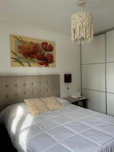 1 dormitorio con cama blanca y lámpara de araña en Departamento Andy, en Villa Carlos Paz