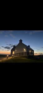 a large white building with a fence in front of it at Lighthouse View in Lochboisdale