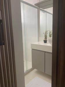 ein weißes Badezimmer mit Waschbecken und Spiegel in der Unterkunft Confortável Apartamento em Angra dos Reis in Angra dos Reis + 7 Fotos