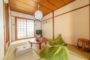 ein Wohnzimmer mit einem Tisch und grünen Stühlen in der Unterkunft GUEST HOUSE Hotori in Ōtsu