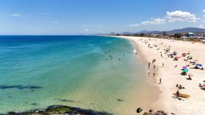 a group of people on a beach with the ocean at Casa Aloha Barra in Maricá