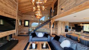 un soggiorno con un divano e un lampadario di Chalet « Le 1712 » direct pistes a Les Angles