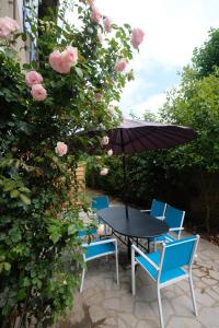a table and chairs with an umbrella and roses at Hippolyte House in Beaune