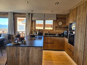 Una cocina con gabinetes de madera y una encimera negra. en Chalet Bliss Jacuzzi vue, en Bolquere Pyrenees 2000