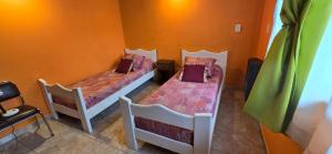 2 Betten in einem Zimmer mit orangefarbenen Wänden in der Unterkunft Valkara Patagonia in Las Golondrinas