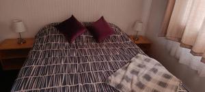 a bedroom with a bed with pillows and two lamps at Cabaña Quemchi in Quemchi