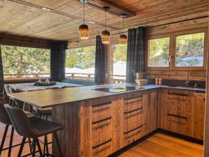 une cuisine avec des placards en bois et un grand îlot dans l'établissement Chalet Colchiques aux pieds des pistes sauna, à Font-Romeu