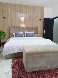 ein Schlafzimmer mit einem großen Bett und einer großen Ottomane in der Unterkunft Brandison Apartments in Port Harcourt