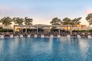 a pool with chairs and umbrellas at a resort at Hyatt Regency Dubai Creek Heights in Dubai