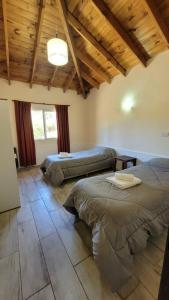 two beds in a room with wooden ceilings at El Cantar de los Pajaros in Merlo +43 photos