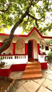 a small red and white house with a tree at Mitra Hostel Vagator in Vagator
