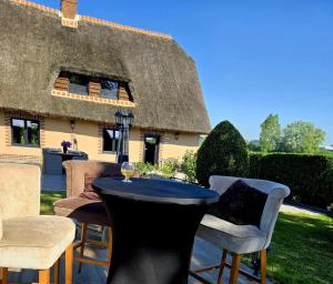 - une table et des chaises en face d'une maison au toit de chaume dans l'établissement La Chaumière de Lilou, Havre de paix en campagne, à Merckeghem
