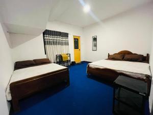 a bedroom with two beds and a blue floor at The Crown's lodge Nuwara Eliya in Nuwara Eliya