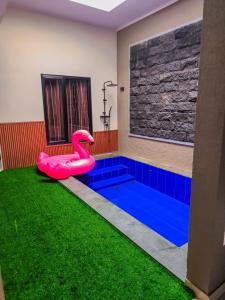 une piscine avec un banc en forme de cygne rose sur la pelouse dans l'établissement Villa nuansa tawangmangu, à Tawangmangu