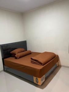 un lit dans une chambre blanche avec des draps et des oreillers marron dans l'établissement Villa nuansa tawangmangu, à Tawangmangu 7 autres photos