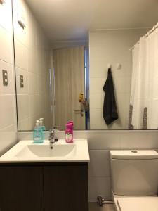 ein Badezimmer mit Waschbecken, Toilette und Spiegel in der Unterkunft Apartment in Iquique, Playa in Iquique