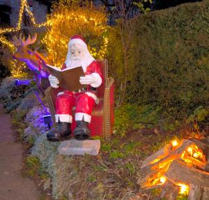 a santa claus sitting in a chair reading a book at Dôme Saint-Eloi in Floursies