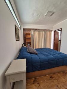 ein Schlafzimmer mit einem blauen Bett und einem Tisch in der Unterkunft Depto Del Centro in San Salvador de Jujuy