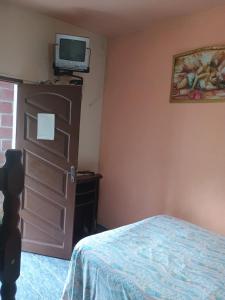a bedroom with a bed and a tv on the wall at Pousada Simone Paulista in Paraty
