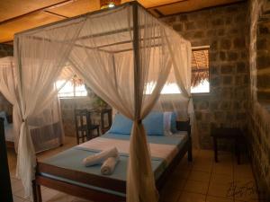 Mora Mora Resort في Ankoalamare: غرفة نوم مع سرير مظلة مع ناموسيات