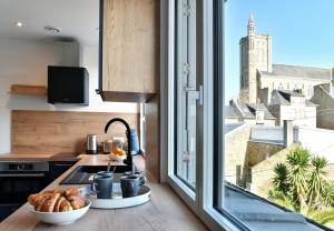 une cuisine avec une fenêtre donnant sur une église dans l'établissement La Plage du Petit Port, à Cancale
