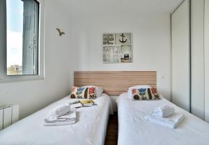 Ce lit se trouve dans un dortoir doté de murs blancs et d'une fenêtre. dans l'établissement La Plage du Petit Port, à Cancale