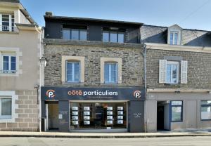 un bâtiment en briques avec une enseigne de praticien du café dessus dans l'établissement La Plage du Petit Port, à Cancale 8 autres photos