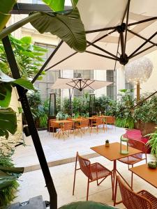 un patio esterno con tavoli, sedie e ombrelloni di Maison Roma Piazza di Spagna UNA Esperienze a Roma
