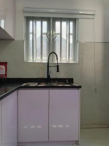 eine Küche mit Spüle und Fenster in der Unterkunft Brandison Apartments in Port Harcourt + 8 Fotos