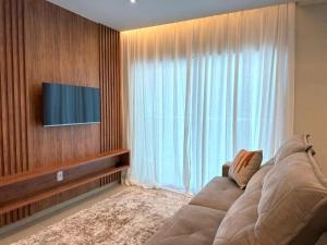 un salon avec un grand canapé et une télévision dans l'établissement Apartamento mobiliado Beira-Mar, à Maragogi