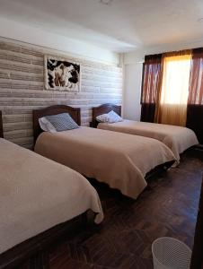 乌尤尼Hostal de Sal Noritha的砖墙间内的三张床