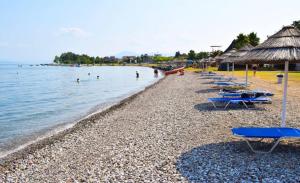 a beach with chairs and people swimming in the water at Lily's Apartment in Kamena Vourla