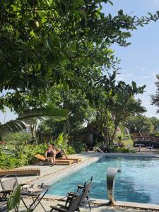 a woman chilling by a swimming pool at a resort at TamCoc Moon An Bungalow & Cafe in Ninh Binh