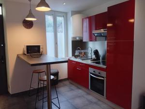 a small kitchen with red cabinets and a small table at Aux portes de l'Eure in Bonnières-sur-Seine