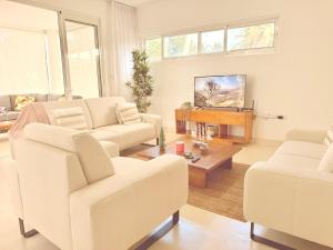 un salon avec deux fauteuils blancs et une télévision dans l'établissement Charming Villa GUGI in Playa Coson, à Las Terrenas