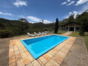 a swimming pool in a yard with chairs and a house at Rancho c/ piscina, churrasqueira, natureza e lazer in Batatuba