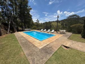 a swimming pool with two chairs and a table at Rancho c/ piscina, churrasqueira, natureza e lazer in Batatuba