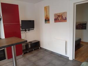 a living room with a tv and a kitchen at Aux portes de l'Eure in Bonnières-sur-Seine