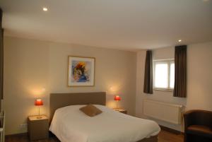 a bedroom with a white bed and a window at De Kruishoeve in De Haan
