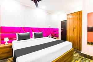 a bedroom with a large bed with a pink headboard at Hotel O Barsana in Pātipukur