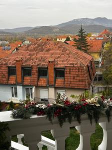 a house with a tile roof with flowers on a fence at Jordan Apartman in Niška Banja