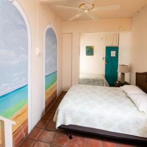 - une chambre avec un lit et une peinture sur la plage dans l'établissement Trade Winds Restaurant & Guest House, à Vieques