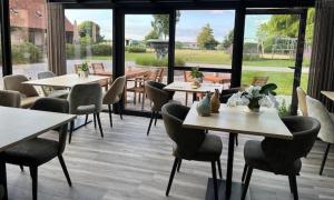 a restaurant with tables and chairs and a large window at De Kruishoeve in De Haan